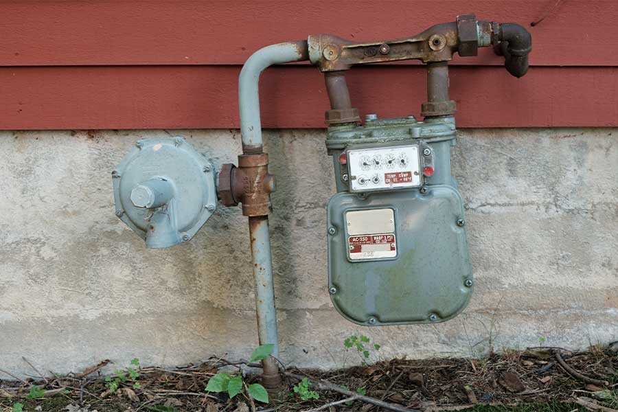 Outdoor gas meter and regulator mounted on a house exterior wall