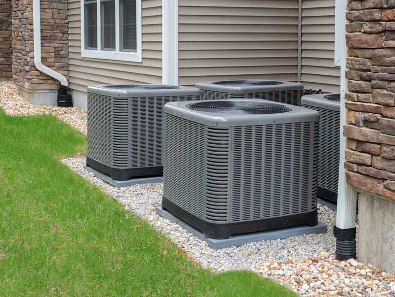 Four outdoor AC units installed beside a house