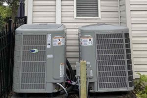 Two outdoor air conditioning units next to a home